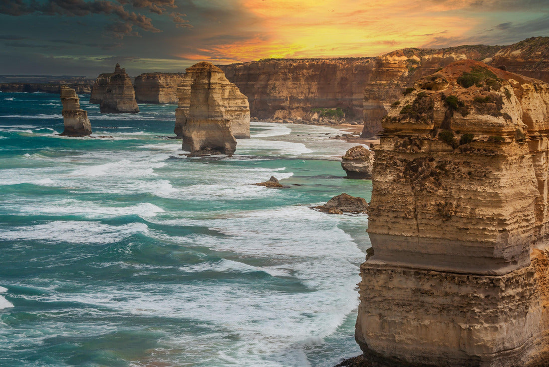 Blue green ocean and beach with sandbanks cliffs and waves with close view of The twelve apostles and cliffs in the shadow of the sunset in Victoria, Australia against a orange cloudy sky 2000pc Puzzle