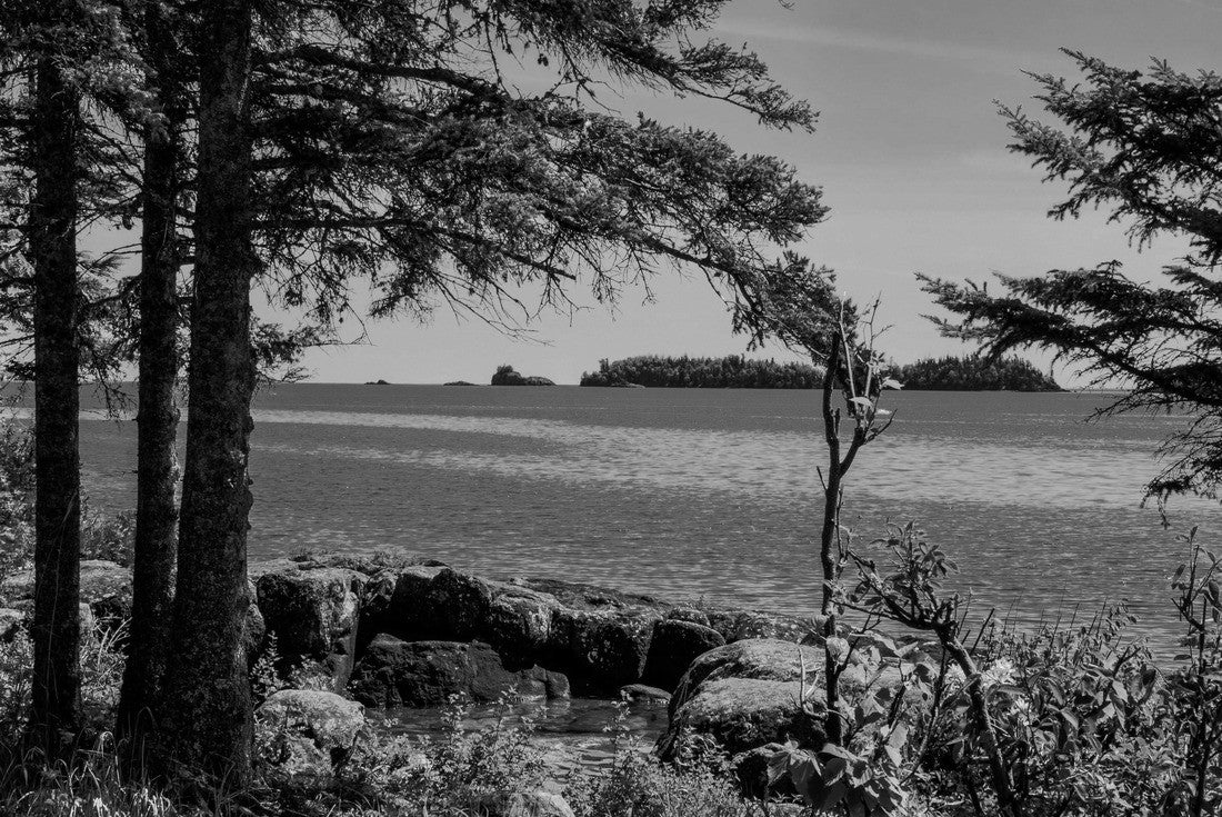 A view through the forest shows several of the tiny islands off the main island of Isle Royale NP in Lake Superior off Copper Harbor, MI. Large boulders surround a little water pool on shoreline 2000pc PuzzleBlack and White