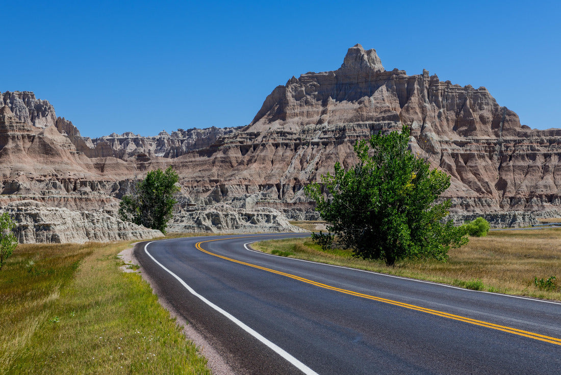 A highway leads through a beautiful grass landscape to a colorful summit in the Badlands National Park, South Dakota 2000pc Puzzle