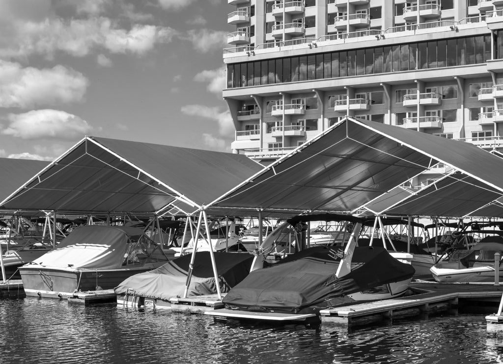 Boats in their covered slips in the marina and boardwalk of a downtown lakefront resort in the Inland Northwest town of Coeur d'Alene, Idaho, USA in black white