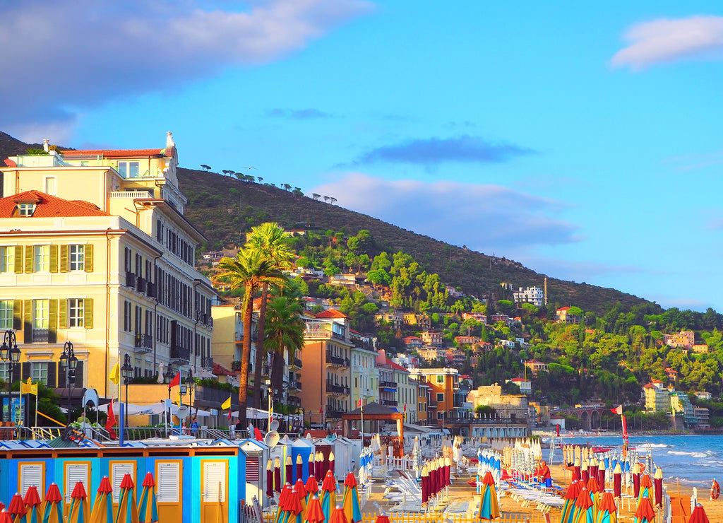 Multicolored parasols on the beach in Alassio, province of Savona, Sanremo region, Italy. Town at sunset