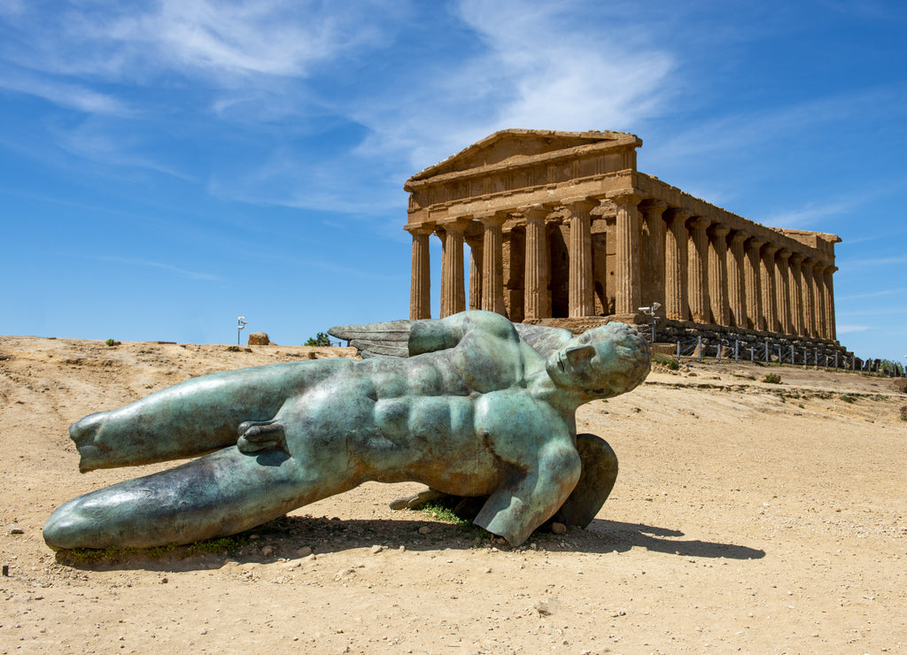 Bronze statue of Icarus in front of the ruins of the Temple of Concordia in the Valley of the Temples near Agrigento on the Italian island of Sicily