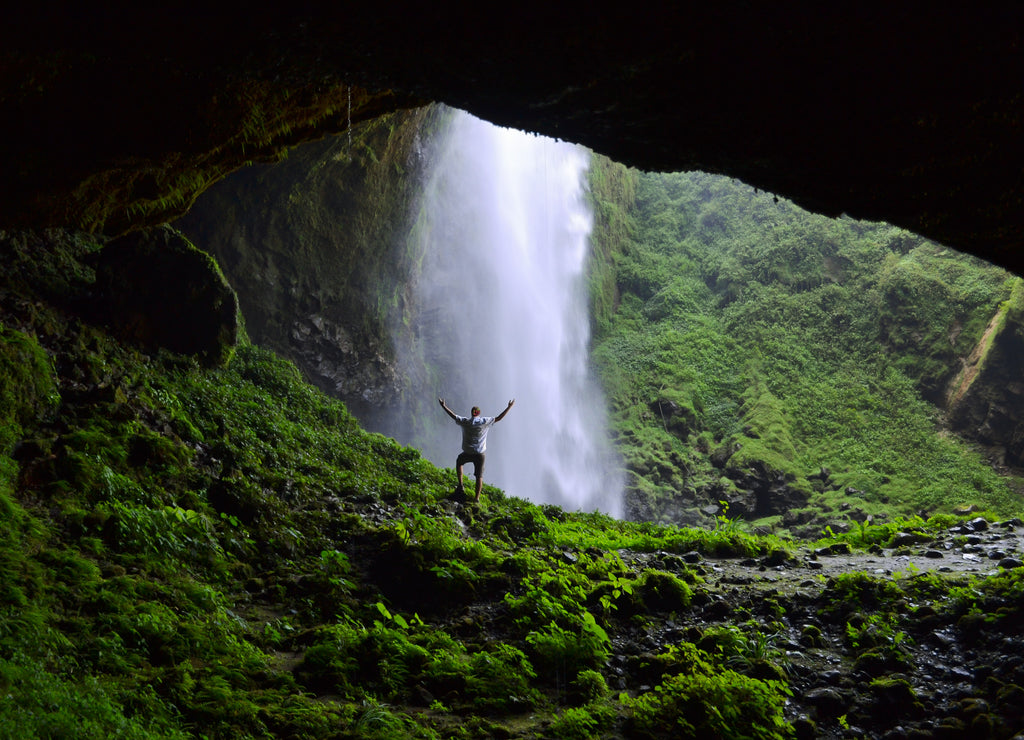 Man admiring Puxtla waterfall with arms in the air near Tlatlauquitepec, Mexico