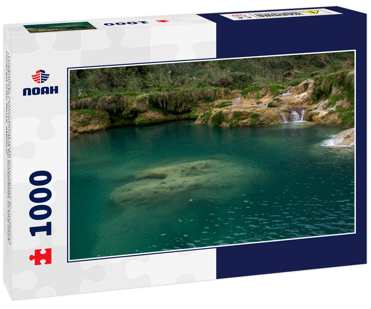 Turquoise water pool with limestone formations underwater surrounded by waterfalls in the rock covered with ferns, Mexico