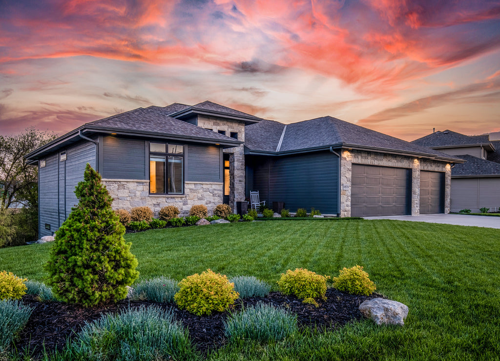 Luxury home during twilight golden hour with pink and purple sky and lush landscaping in Nebraska USA