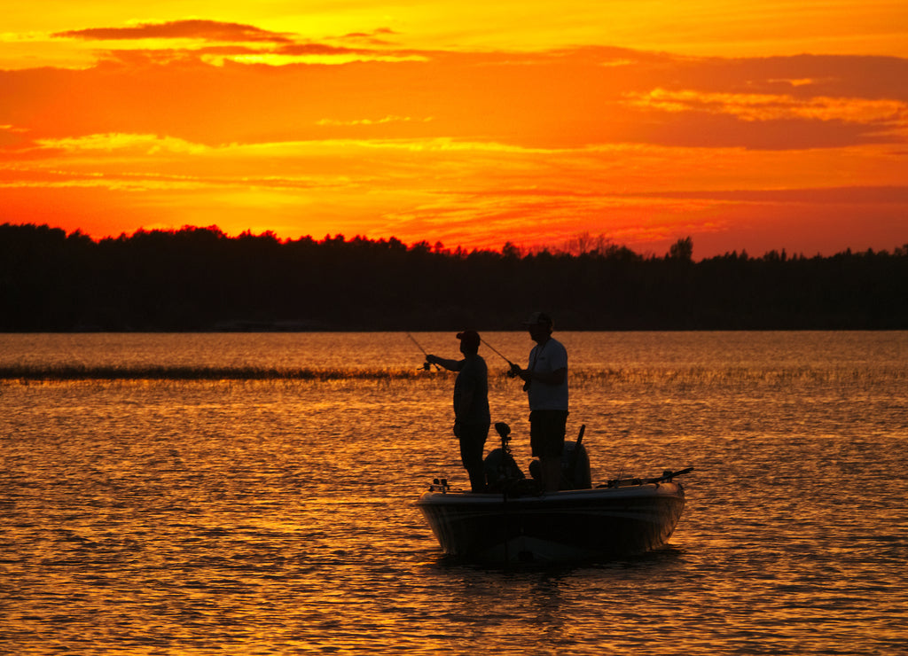 Silhouette of men fishing in a boat on a lake just after sunset in Bemidji Minnesota