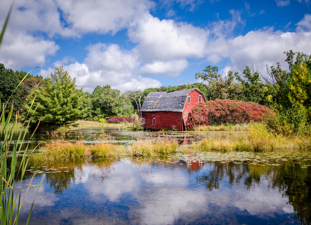 An abandoned red sinking barn sinks into a lake near Zimmerman, Minnesota