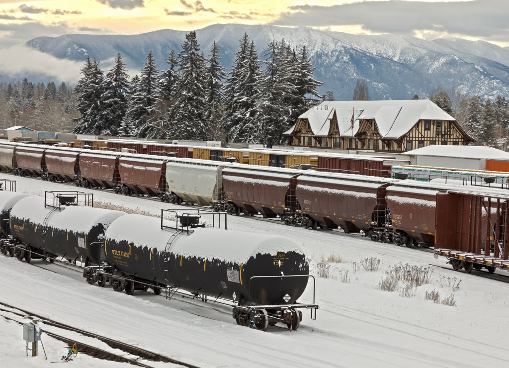 Rail yard in winter with trains, depot, and mountains in background, whitefish, Montana
