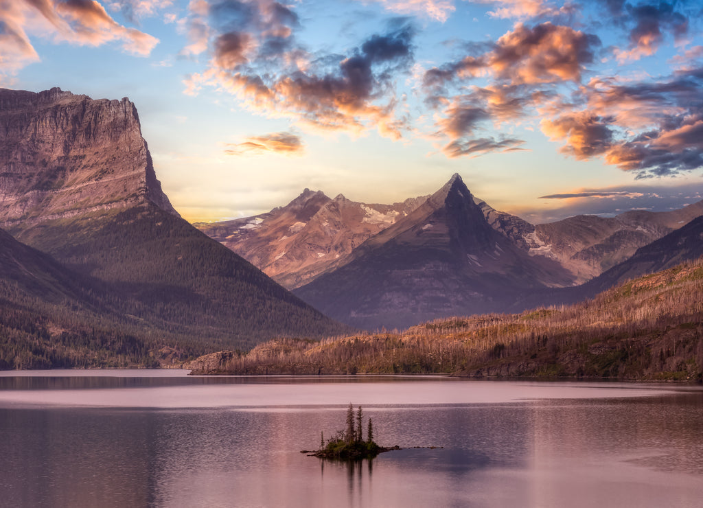 Beautiful Panoramic View of a Glacier Lake with American Rocky Mountain Landscape in the background. Dramatic Colorful Sunrise Sky. Taken in Glacier National Park, Montana, United States