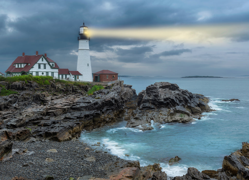 Lighthouse beam light in stormy clouds. Portland Head Light, Maine, USA