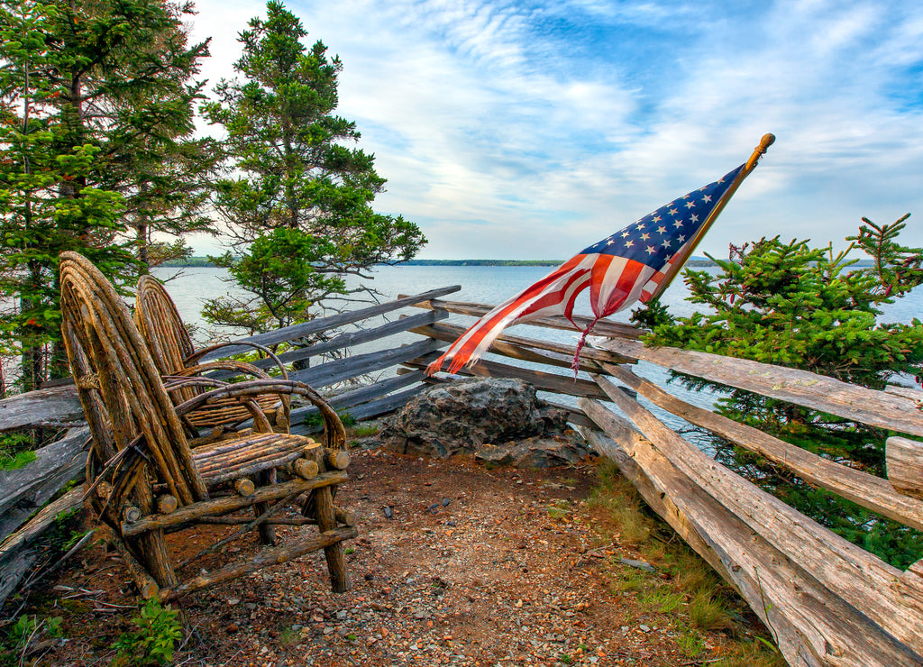 Rustic willow twig chairs and American flag overlooking ocean. Acadia, Maine