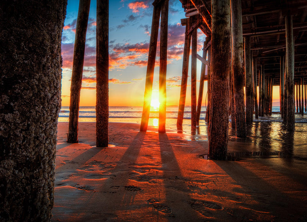 Sun shines through the pilings under the wooden pier at the Old Orchard Beach, Saco Bay, Maine USA