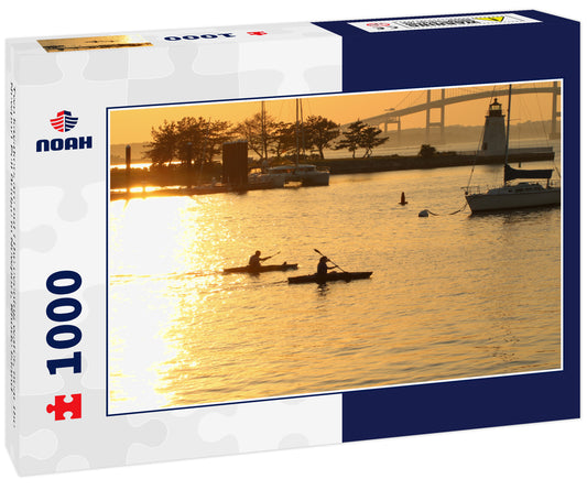 Two kayakers are out i the evening water, near the Newport Pell Bridge in Newport, Rhode Island