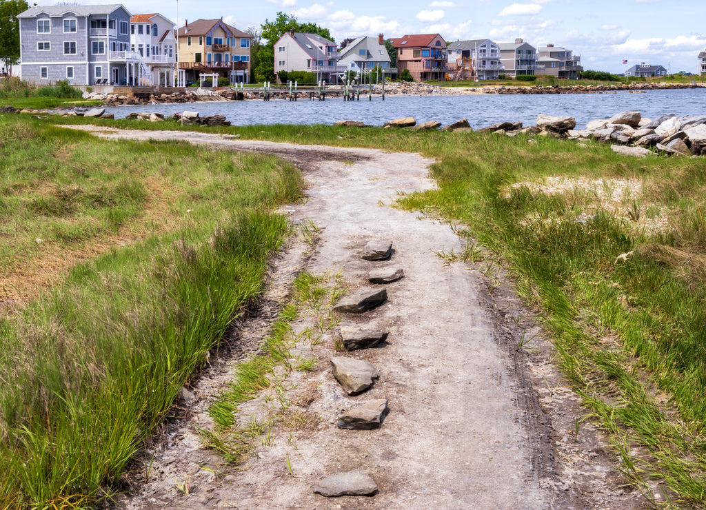 Coastal gravel road with the small seaside neighborhood on the background in East Greenwich, Rhode Island