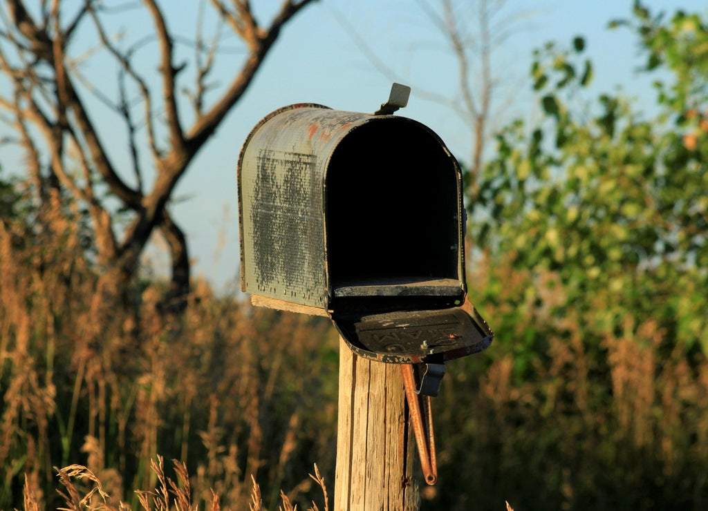 Kansas Rural route mailbox with grass and tree's out in the country east of Sterling Kansas USA with blue sky