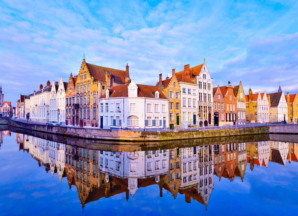 Cityscape view of Bruges and traditional houses reflected in water at sunrise in Belgium