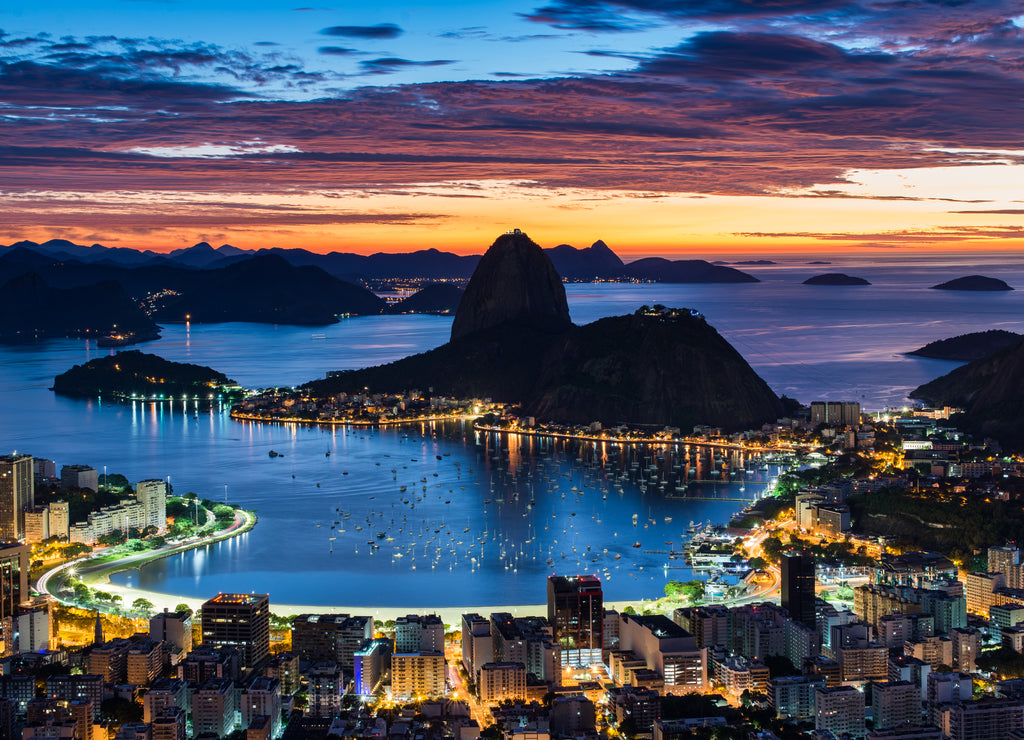 Rio de Janeiro city just before sunrise with city lights on, and the Sugarloaf Mountain in the horizon