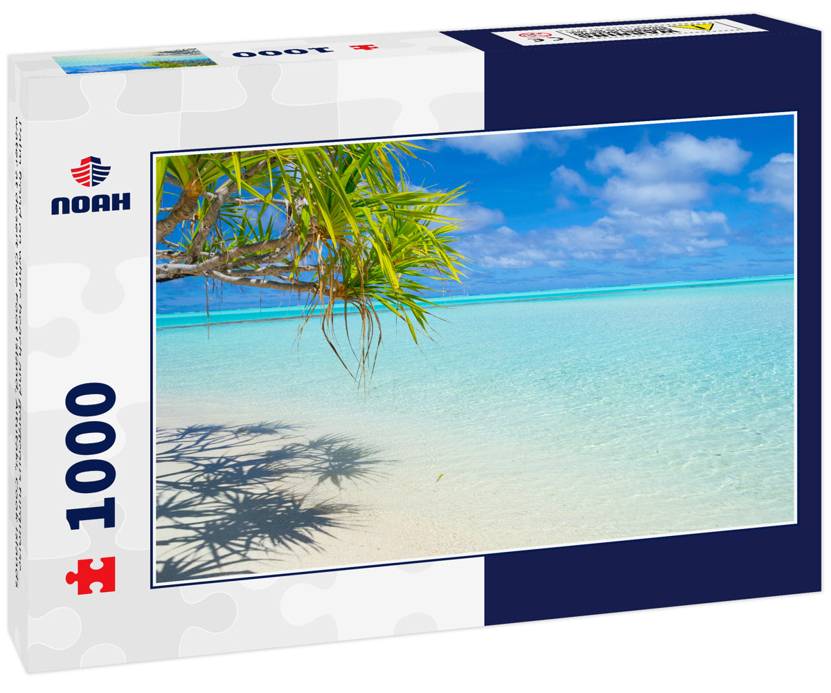 Palm frond on white beach and gorgeous turquoise water at desert One Foot Island, Aitutaki, Cook Islands