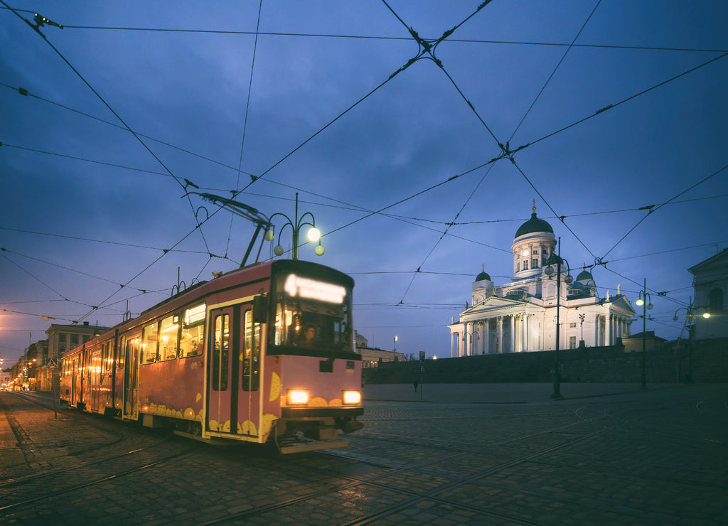Tram passing Helsinki Senate Square during sunset with Helsinki Cathedral in the background at Finland