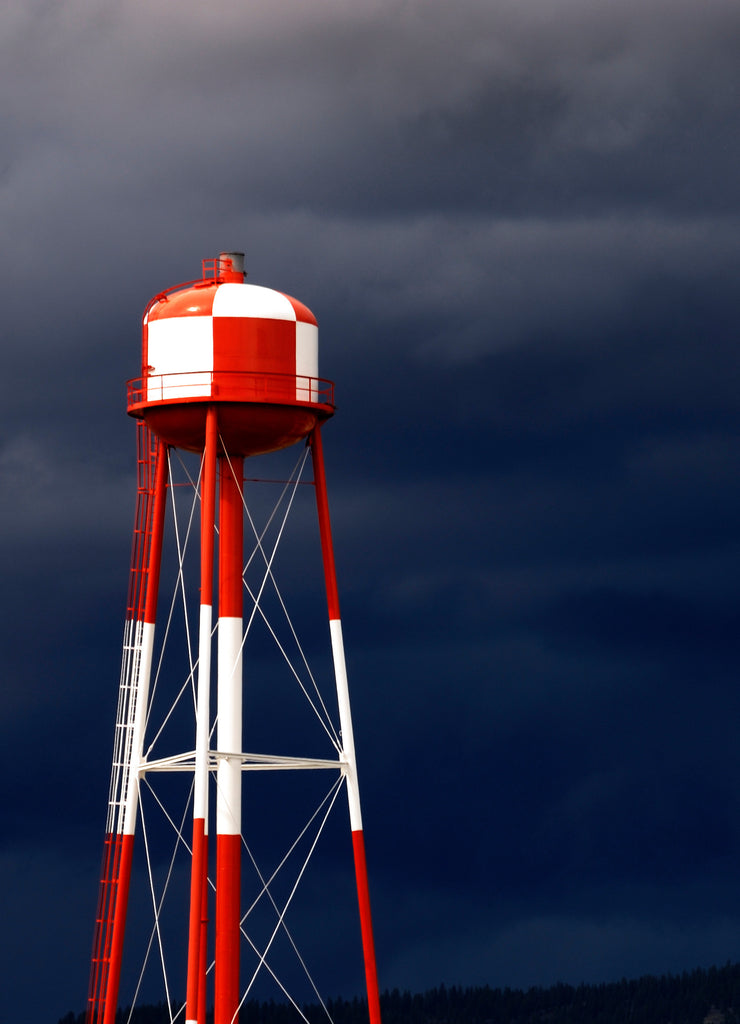 A modern red and white water tower against a cloudy, stormy sky in Spokane Valley, Washington, USA