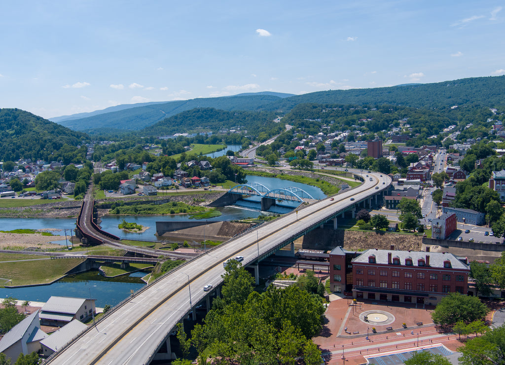 Interstate 68 passes through Cumberland, Allegany County, Maryland. A railroad bridge on the left crosses the Potomac River to Ridgeley, West Virginia