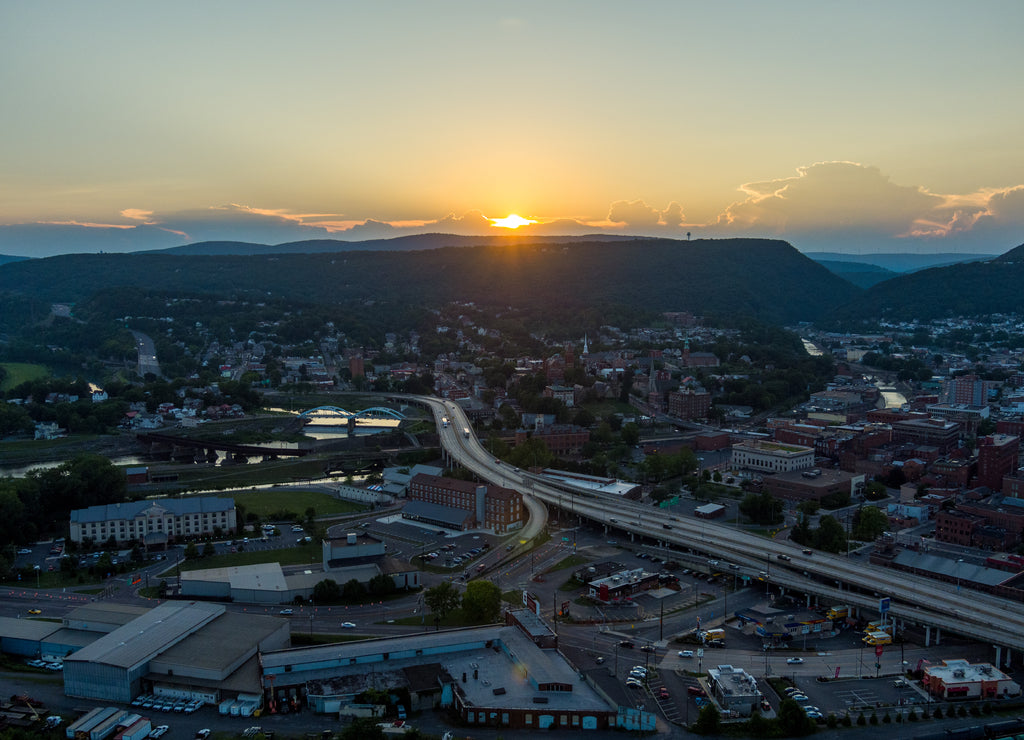 Interstate 68 bisects Cumberland, Allegany County, Maryland. The sun sets behind storm clouds and the Allegheny Mountains