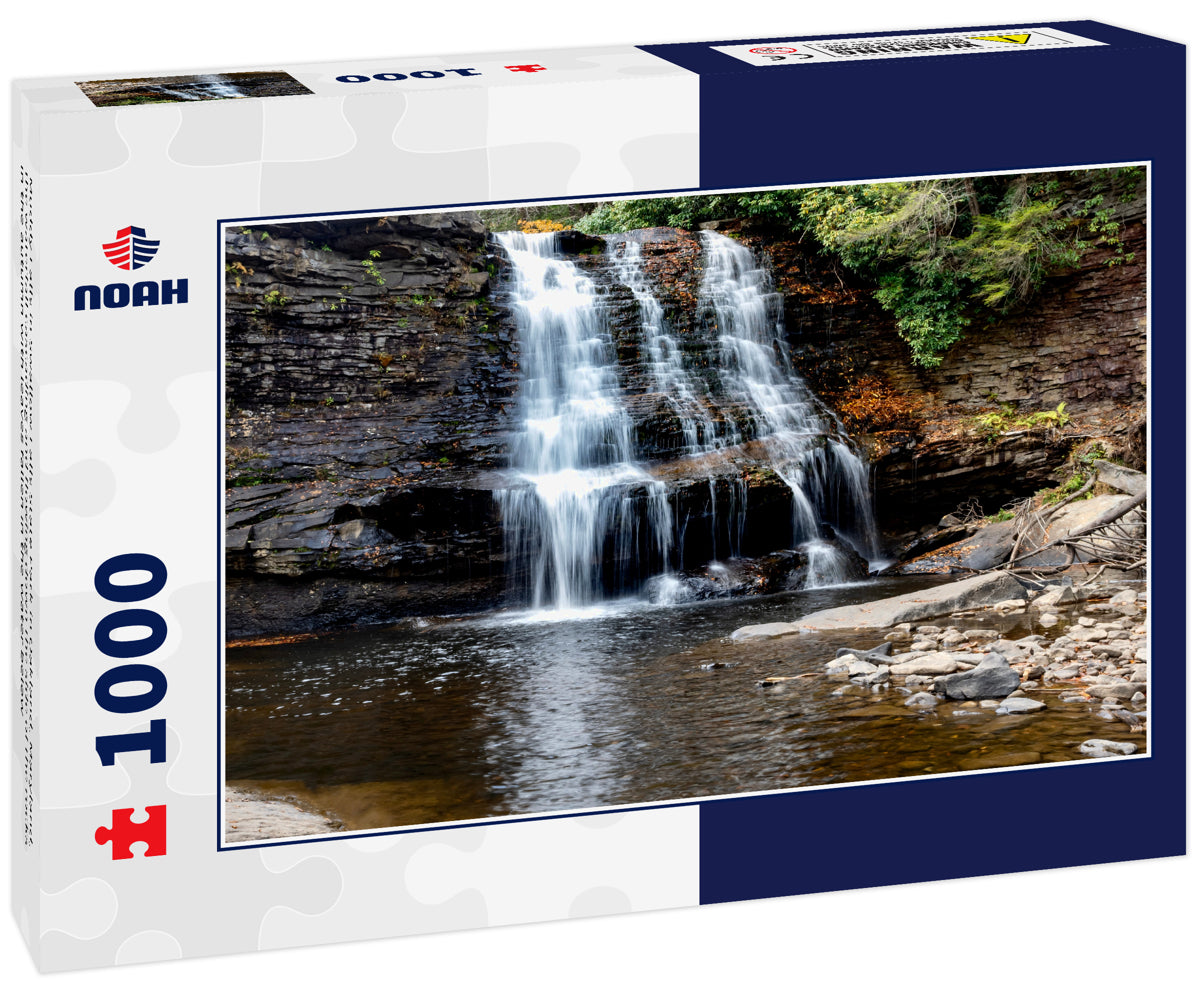 Muddy Falls in Swallow Falls State Park in Oakland, Maryland, the waterfall cascading and flowing down the side of the rocks in the autumn with leaves fallen in the water below