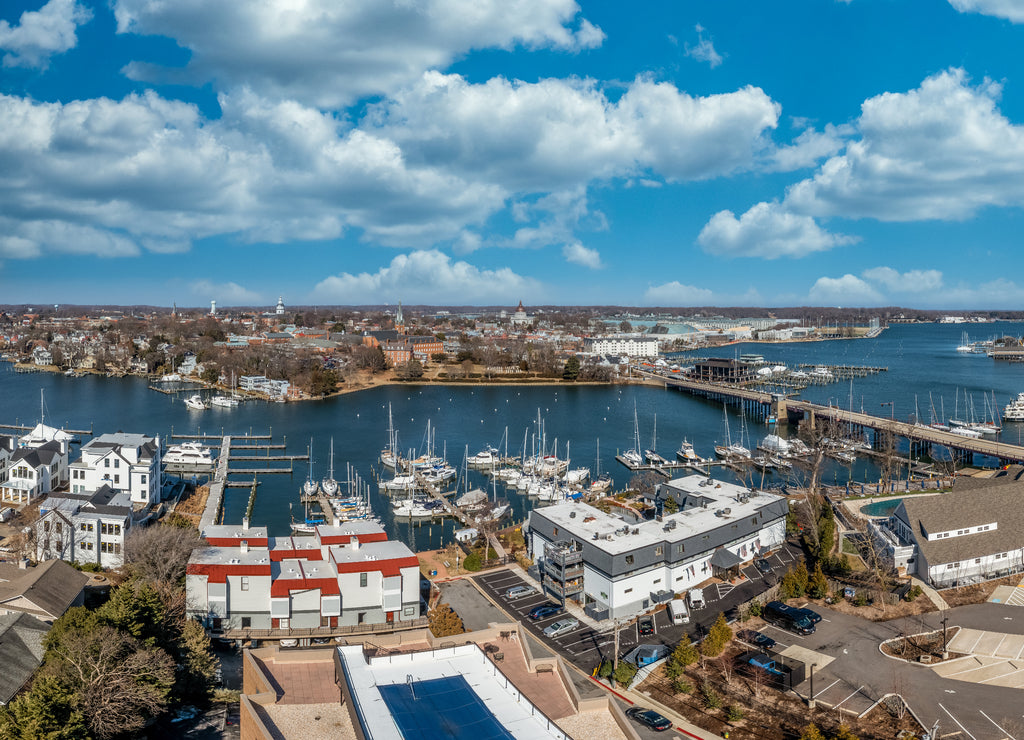 Aerial panorama of Annapolis harbor with luxury sail boats docked in the marina, drawbridge crossing the creek, Maryland state house and Naval Academy, luxury water side houses