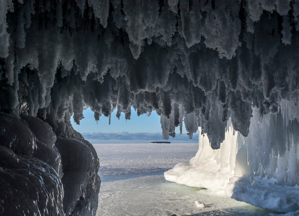 Hoar frost hangs from caves in the sandstone formations on Wisconsin's Apostle Islands National Lakeshore near Meyer's beach; Lake Superior. Eagle island can be seen in the distance