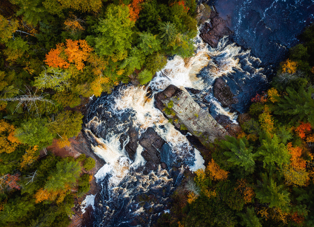 Beautiful look down travel photograph of the upper Potato River Falls waterfall cascades and whitewater rapids cutting through the deciduous and evergreen forest wilderness in Wisconsin