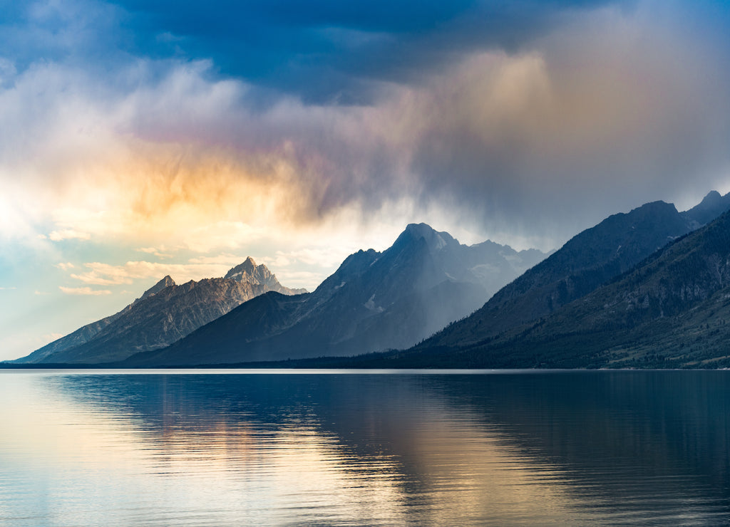 Reflective lake and rocky mountains in Grand Teton National park under the gloomy sky in Wyoming