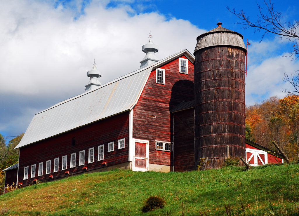 A long barn stands on top of a hill in Autumn on a Vermont farm