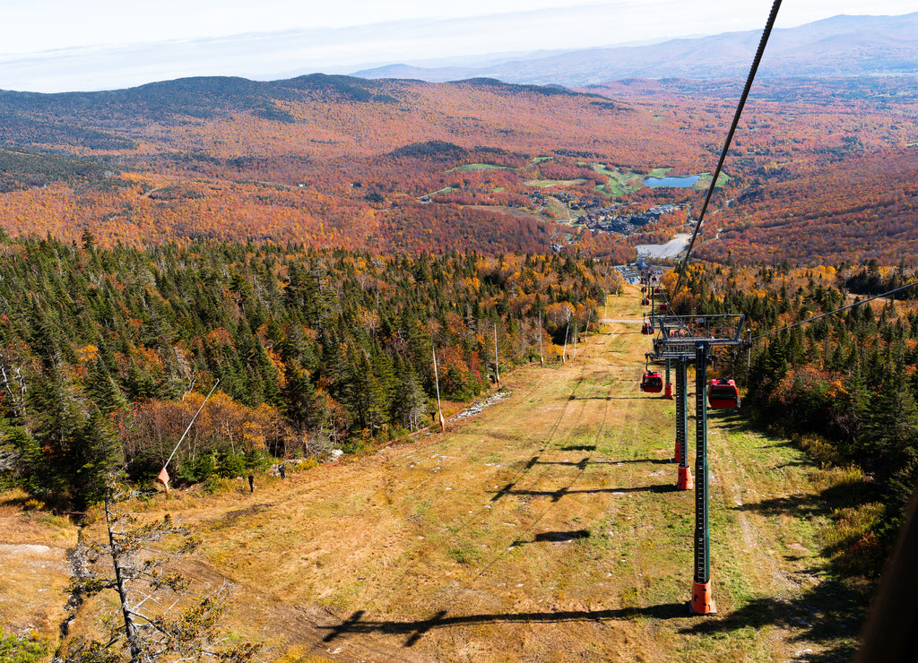 Cable car view. Fall colour seen from above, with telephoto lens, on Stowe Mountains in Vermont, US. A forest of trees turning red and orange