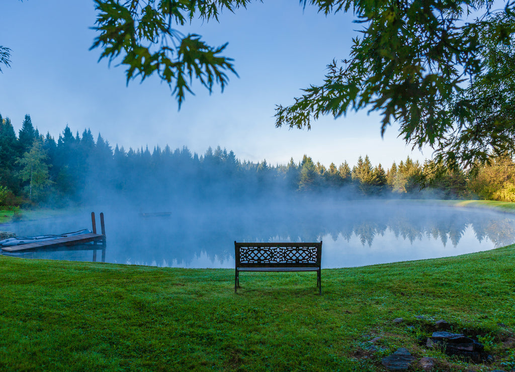 A decorative bench in front of a foggy pond, Stowe Vermont, USA