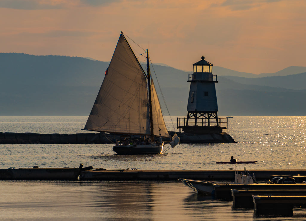 a sloop sailing by the lighthouse on the waterfront of Lake Champlain in Burlington, Vermont