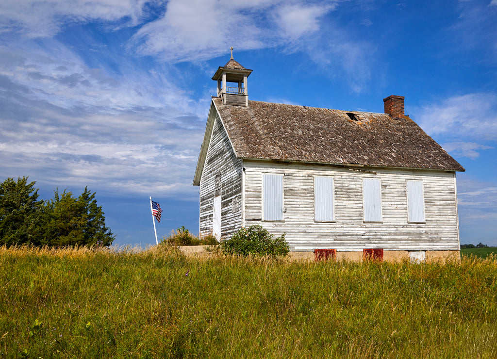 Old white barn majestically sitting on top of a hill against blue sky near Fargo North Dakota
