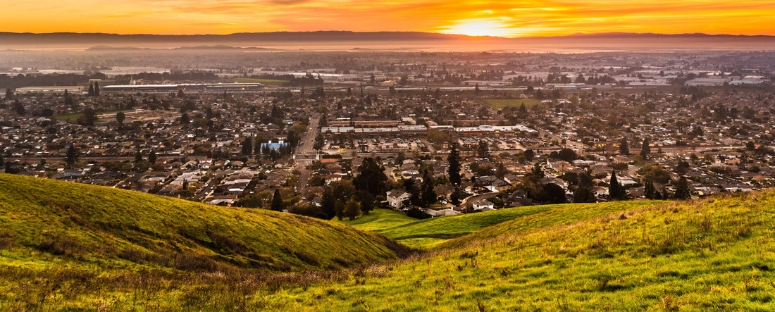 Sunset view of residential and industrial areas in East San Francisco Bay Area; green hills visible in the foreground; Hayward, California 2000pc Panoramic Puzzle