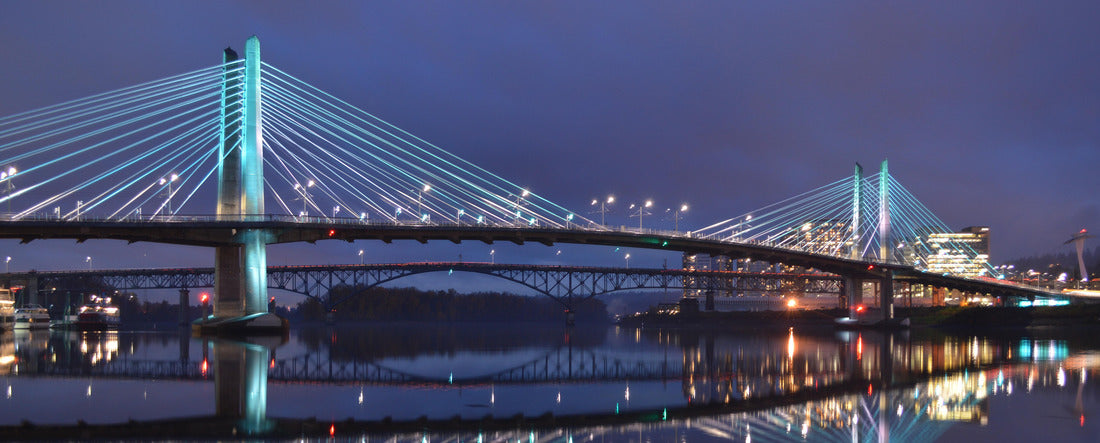 The Tillikum Bridge crosses the Willamette River in Portland, Oregon. The lights from the city's modern structures are reflected in the calm waters 2000pc Panoramic Puzzle