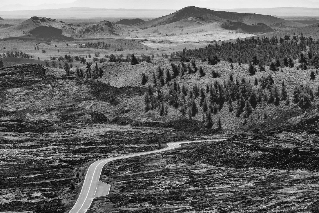 Road that runs between lava rocks and grasslands with pine trees. Craters of the Moon National Monument and Preserve is a United States National Monument and National Preserve on the Snake River Plain 2000pc PuzzleBlack and White
