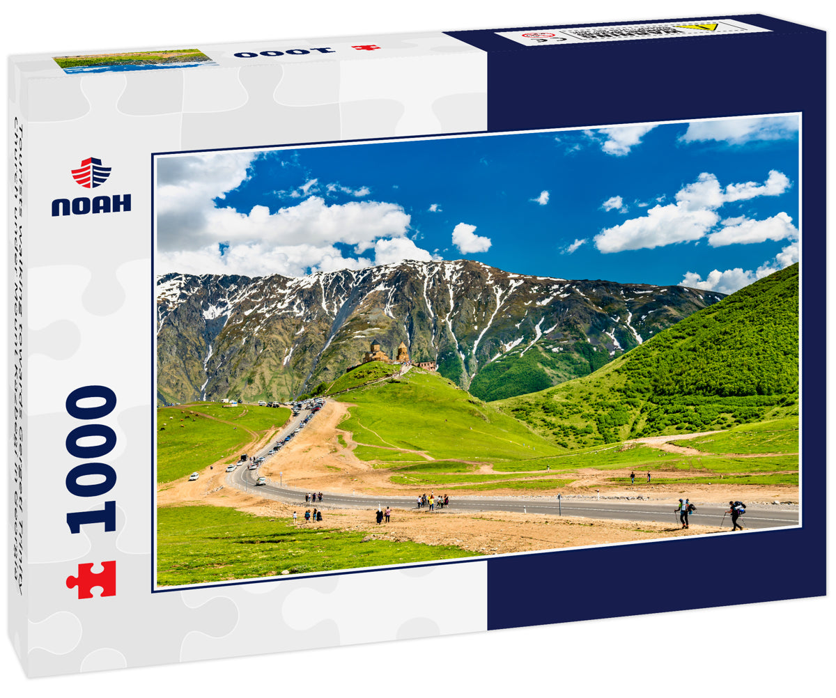 Tourists walking towards Gergeti Trinity Church under Mount Kazbegi in Georgia