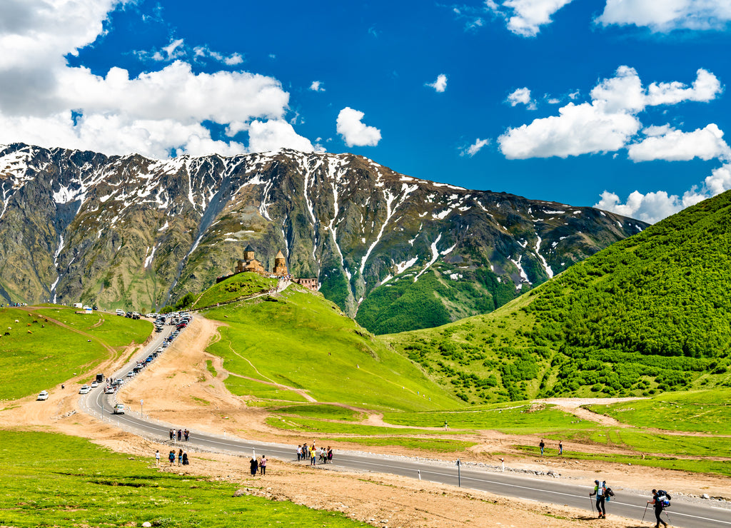 Tourists walking towards Gergeti Trinity Church under Mount Kazbegi in Georgia