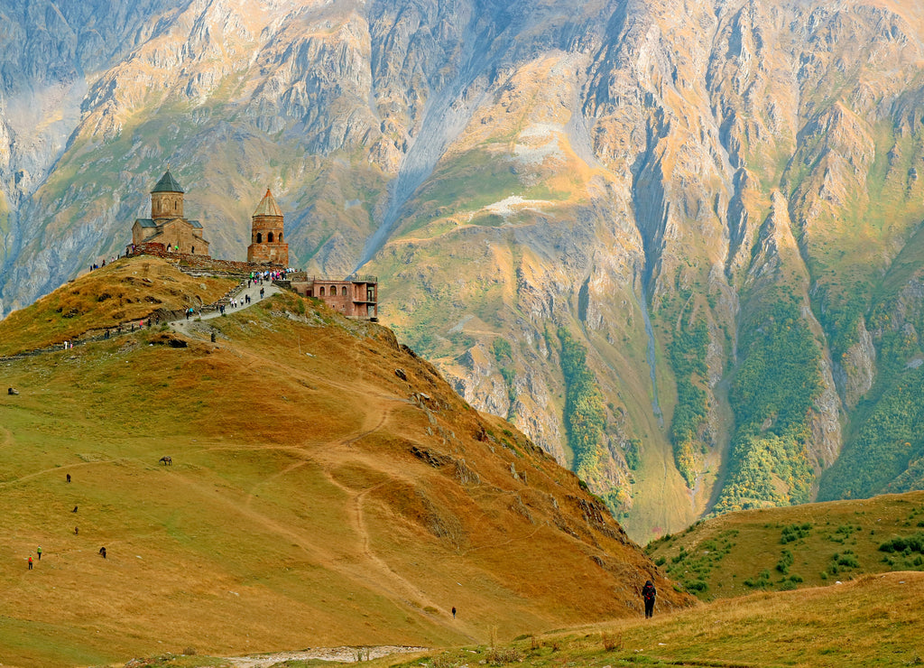 Stunning View of the Gergeti Trinity Church or Tsminda Sameba on the Hilltop with Group of Visitors, Stepantsminda Town, Georgia