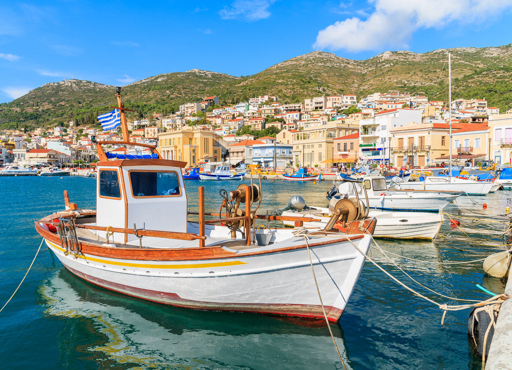 Traditional Greek boat in port of Samos with colourful houses in background, Greece