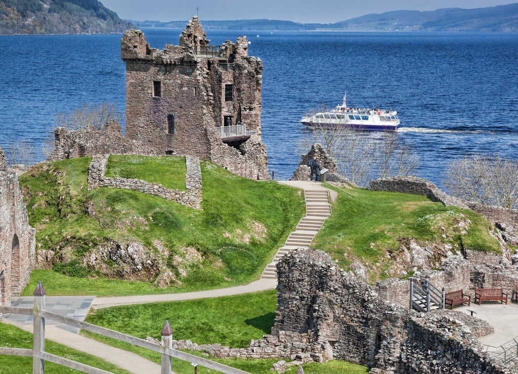 Ruins of Urquhart Castle against boat on Loch Ness in Scotland