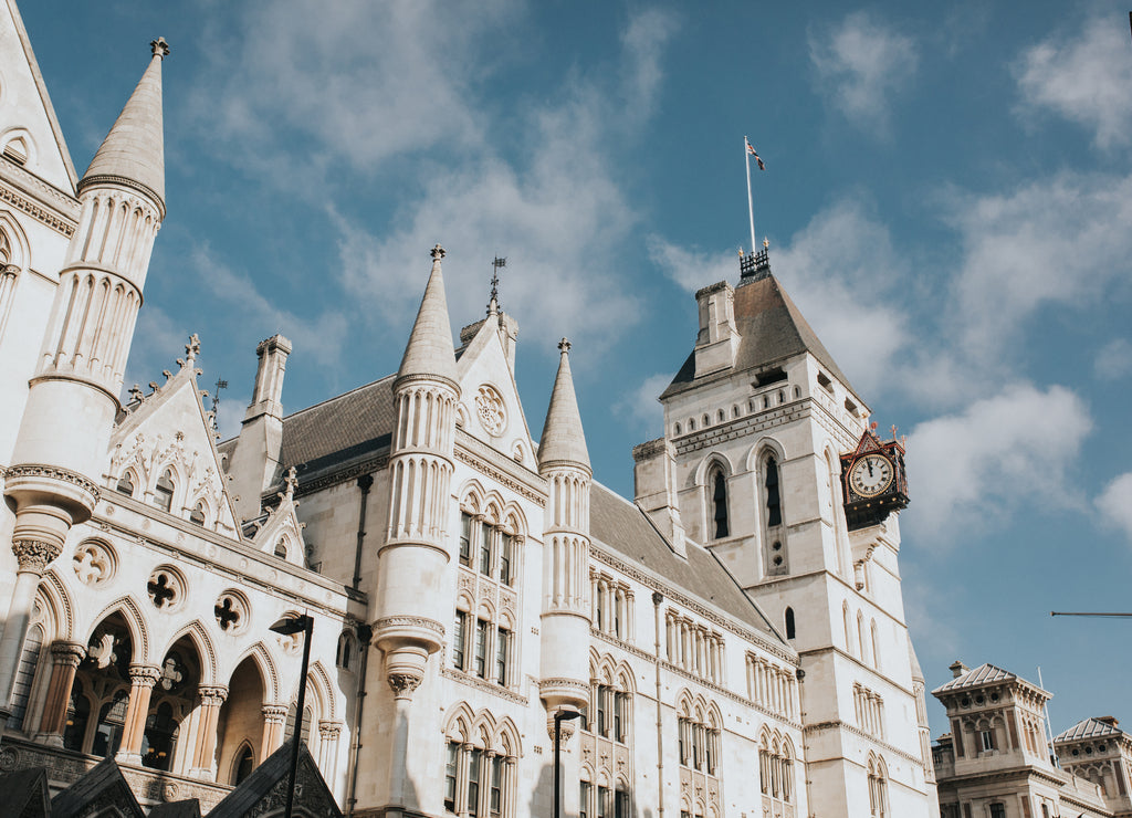 Royal Courts Justice building facade during a sunny day, with blue sky and clouds in the background, in London, United Kingdom