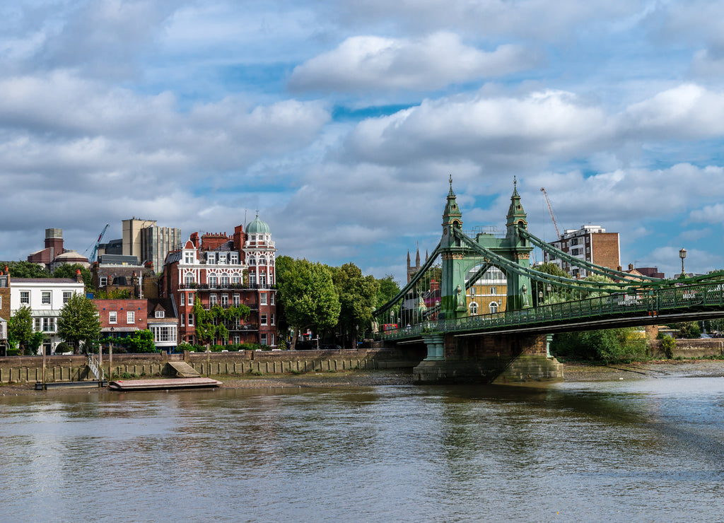 The Hammersmith Bridge, a suspension bridge that crosses the River Thames in west London. Hammersmith is in the background, photo taken from Barnes