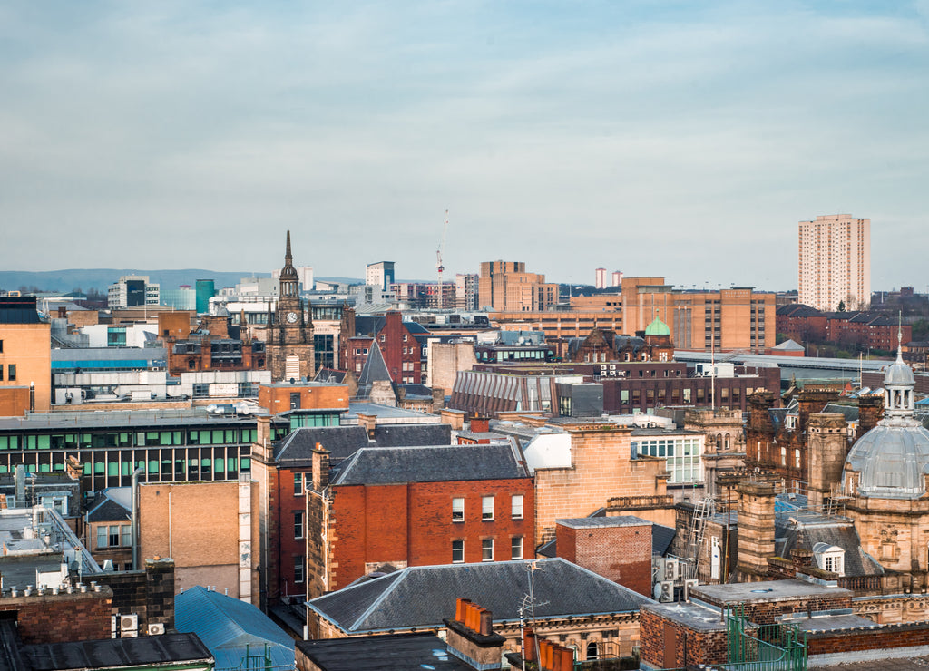 A wide rooftop view looking out over the buildings and architecture of Glasgow city centre in evening light, Scotland