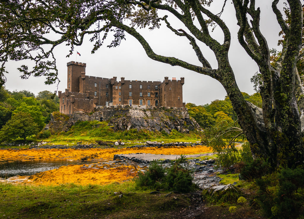 Dunvegan Castle viewed from the gardens, view bordered with tree branches in Dunvegan, Isle of Skye, Scotland
