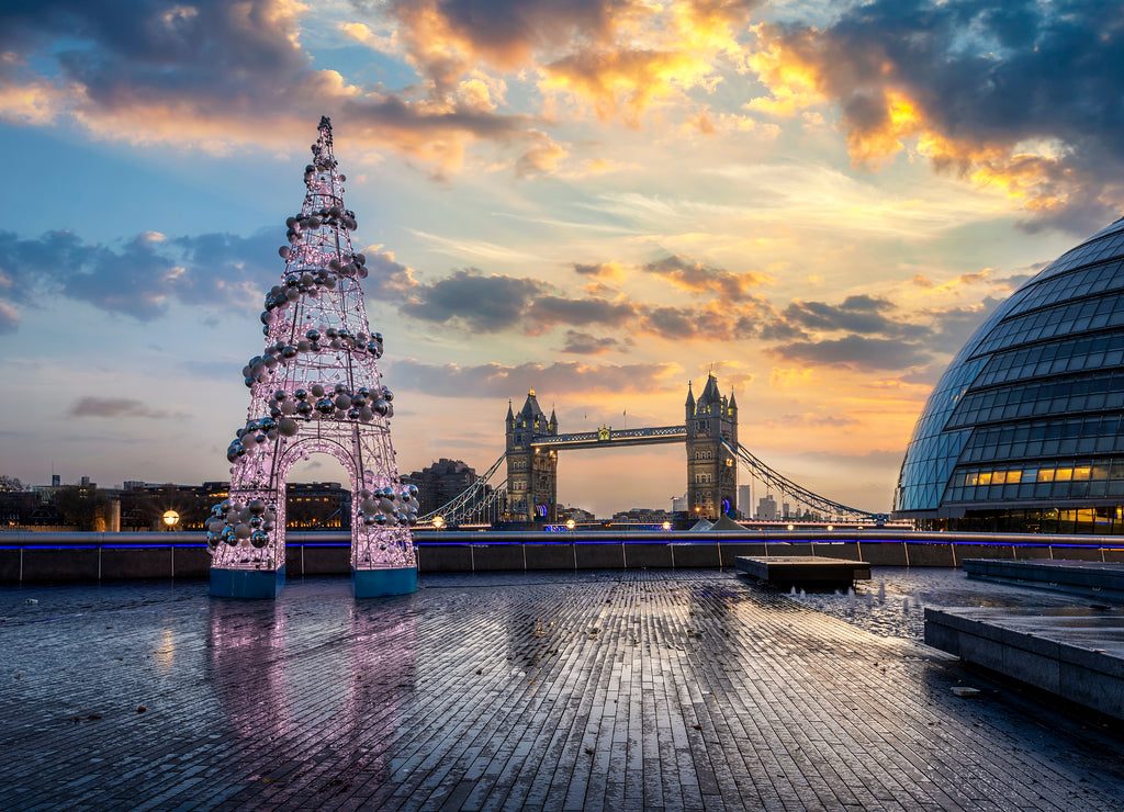 Die Tower Bridge in London, Großbritannien, im Winter bei Sonnenaufgang mit einem festlich geschmückten Weihnachtsbaum davor