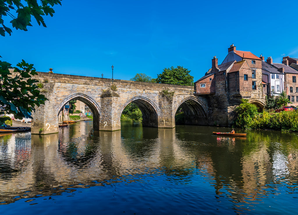 A view through the tree lined shore towards the Elvet Bridge in Durham, UK in summertime